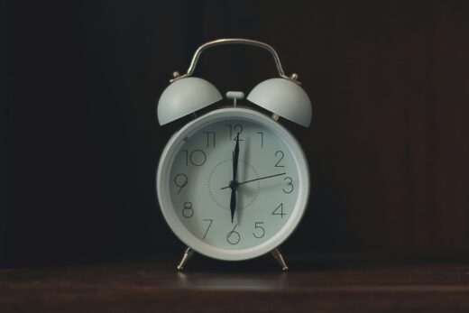 Close-up of a classic white vintage alarm clock on a wooden surface.