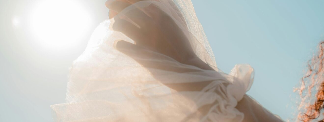 Graceful hands holding a flower against a sunny clear sky, capturing elegance and freedom.