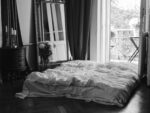 Black and white image of a stylish bedroom with a balcony view, cozy bed, and elegant decor.